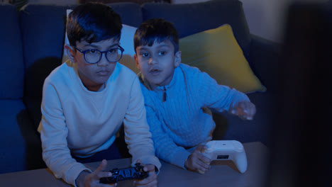 Two-Young-Boys-At-Home-Playing-With-Computer-Games-Console-On-TV-Holding-Controllers-Late-At-Night-4
